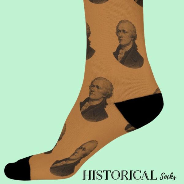 Side view of brown Alexander Hamilton socks worn on feet, engraved portrait design repeated