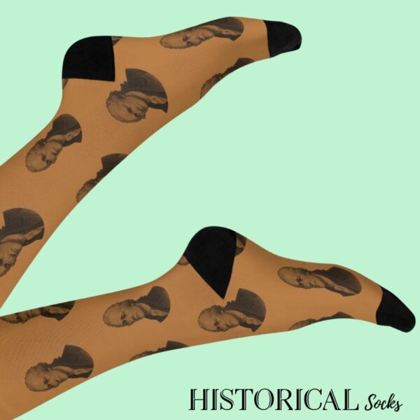 Brown Alexander Hamilton socks with black toe and heel, worn mid-air with crossed legs