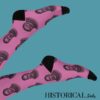 Pink Ernest Hemingway socks worn with legs up – literary-themed fashion with black accents