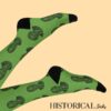 Feet raised wearing green Nelson Mandela socks with black heel and toe, blue background